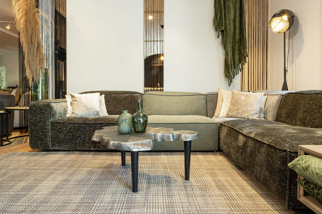 "Stijlvolle fluwelen hoekbank met kussens, ronde salontafel, designer vloerlamp en gedrapeerd gordijn in een chique interieurontwerp met vintage accenten en textuurrijk tapijt."