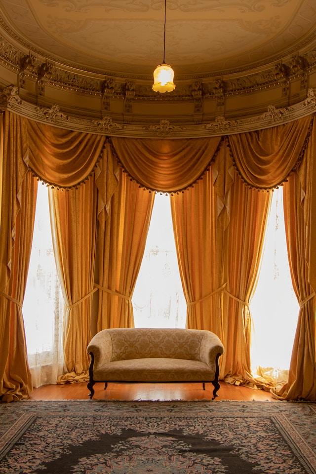 "Elegante klassieke zitkamer met weelderige gouden gordijnen, rococo plafond, vintage sofa en sierlijk tapijt in een historisch herenhuis."