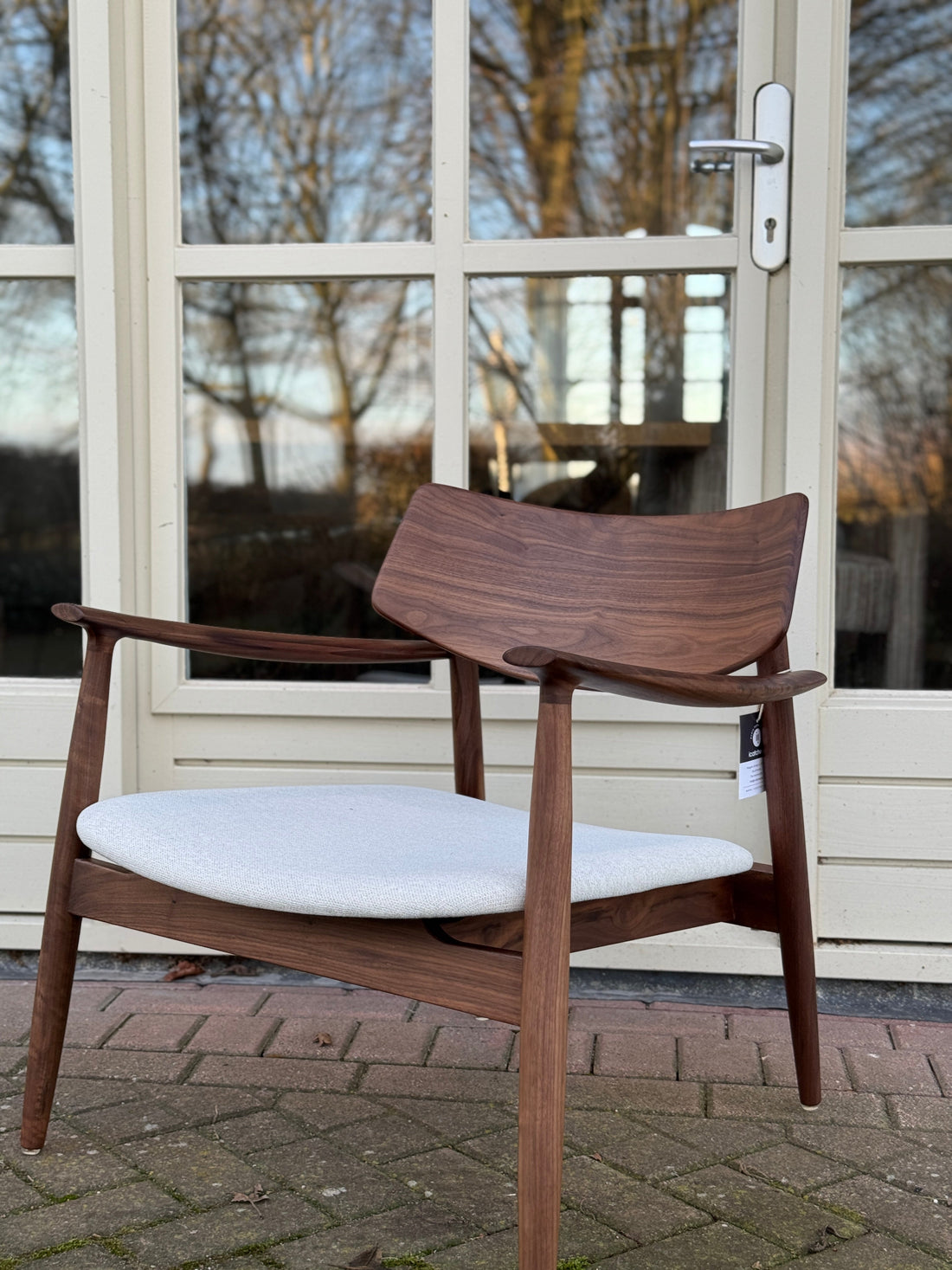 Een stijlvolle, donkerhouten designstoel met lichte zitting staat klaar voor gebruik, perfect passend bij een Scandinavisch interieur.
