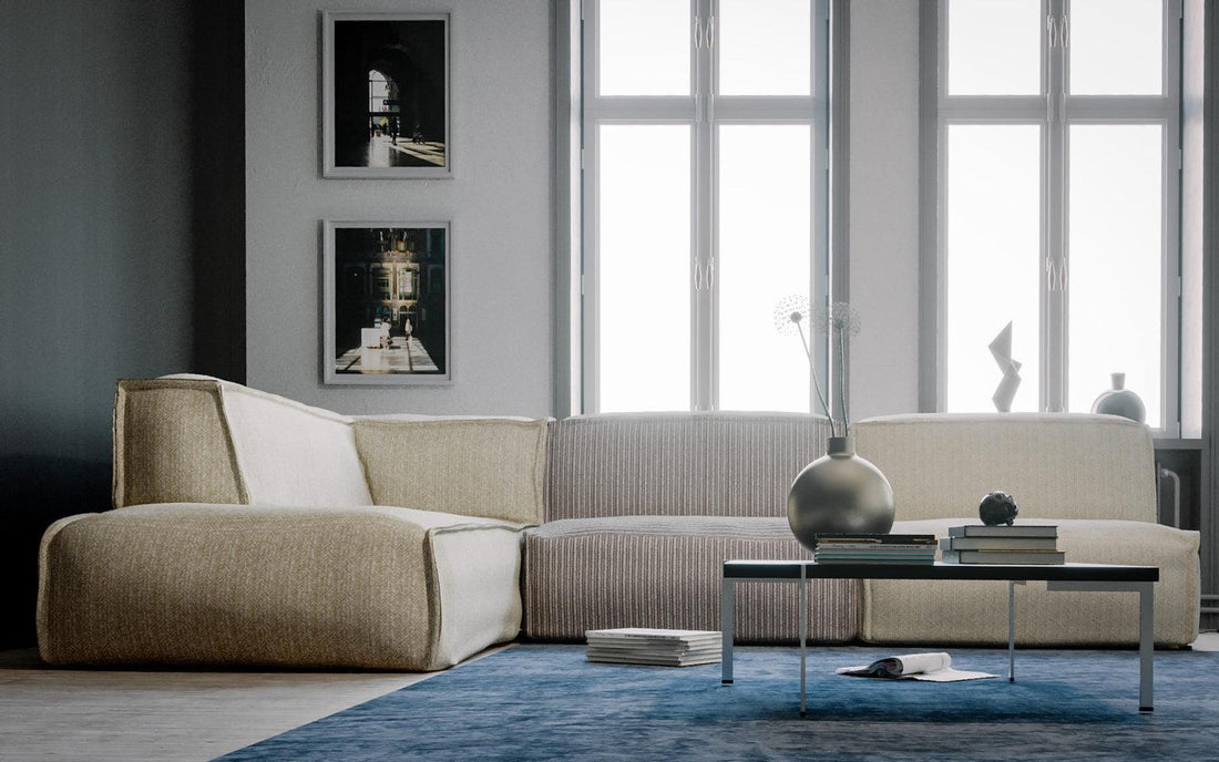 "Eigentijdse woonkamer met comfortabele stoffen hoekbank, grote ramen met veel natuurlijk licht, minimalistische kunst aan de muur, design tafellamp op bijzettafel, stapel koffietafelboeken en abstracte beeldhouwkunst."