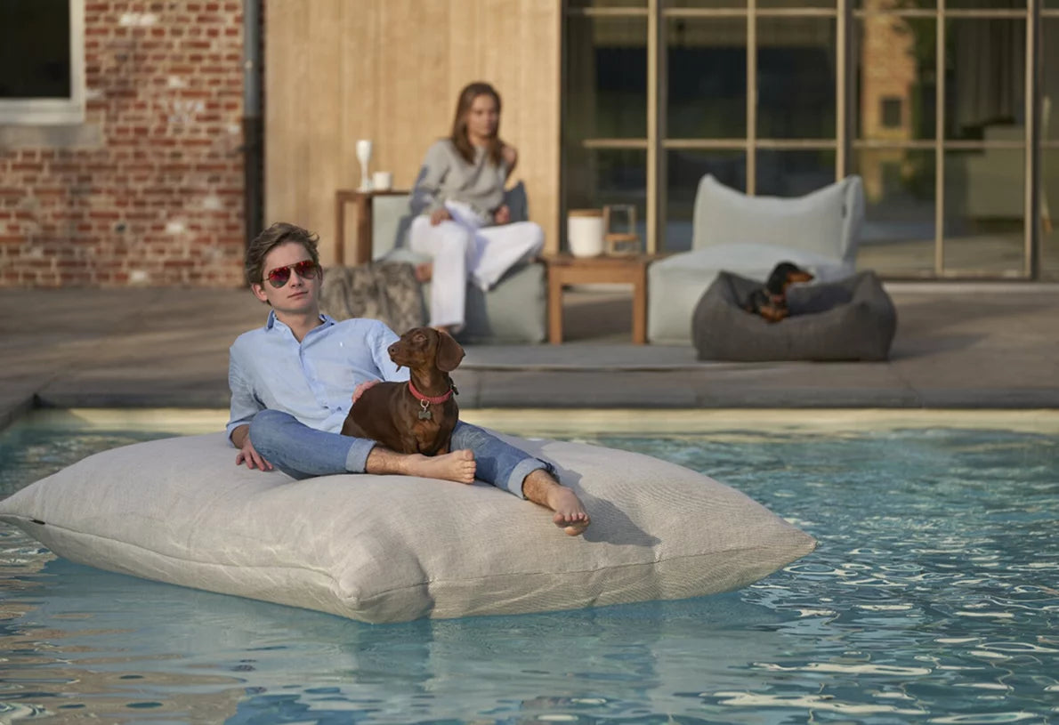 Outdoor lounge seat by HoekbankXXL, shown in light gray in a lifestyle setting by the pool.