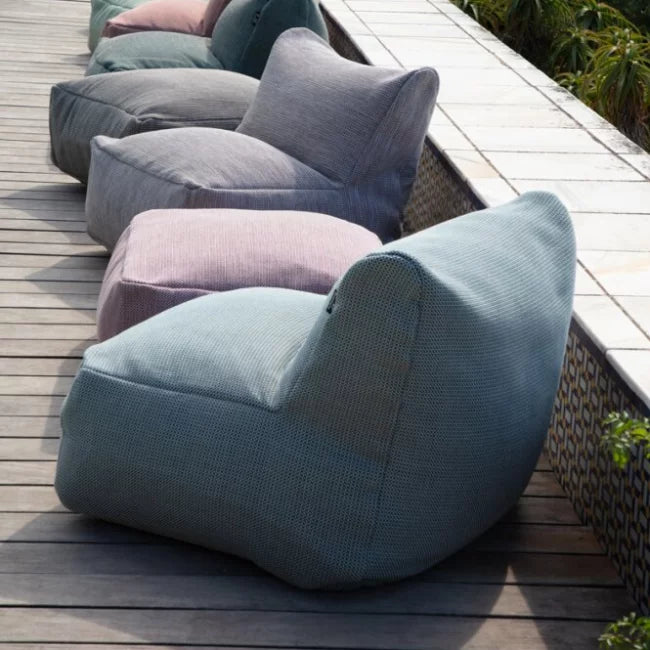 Dotty outdoor lounge seats by HoekbankXXL in a variety of colors, arranged on a wooden deck next to a patterned ledge.
