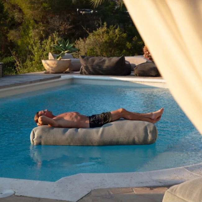 Gray outdoor seat loungebank tuin by HoekbankXXL in a pool, with a man relaxing on it.