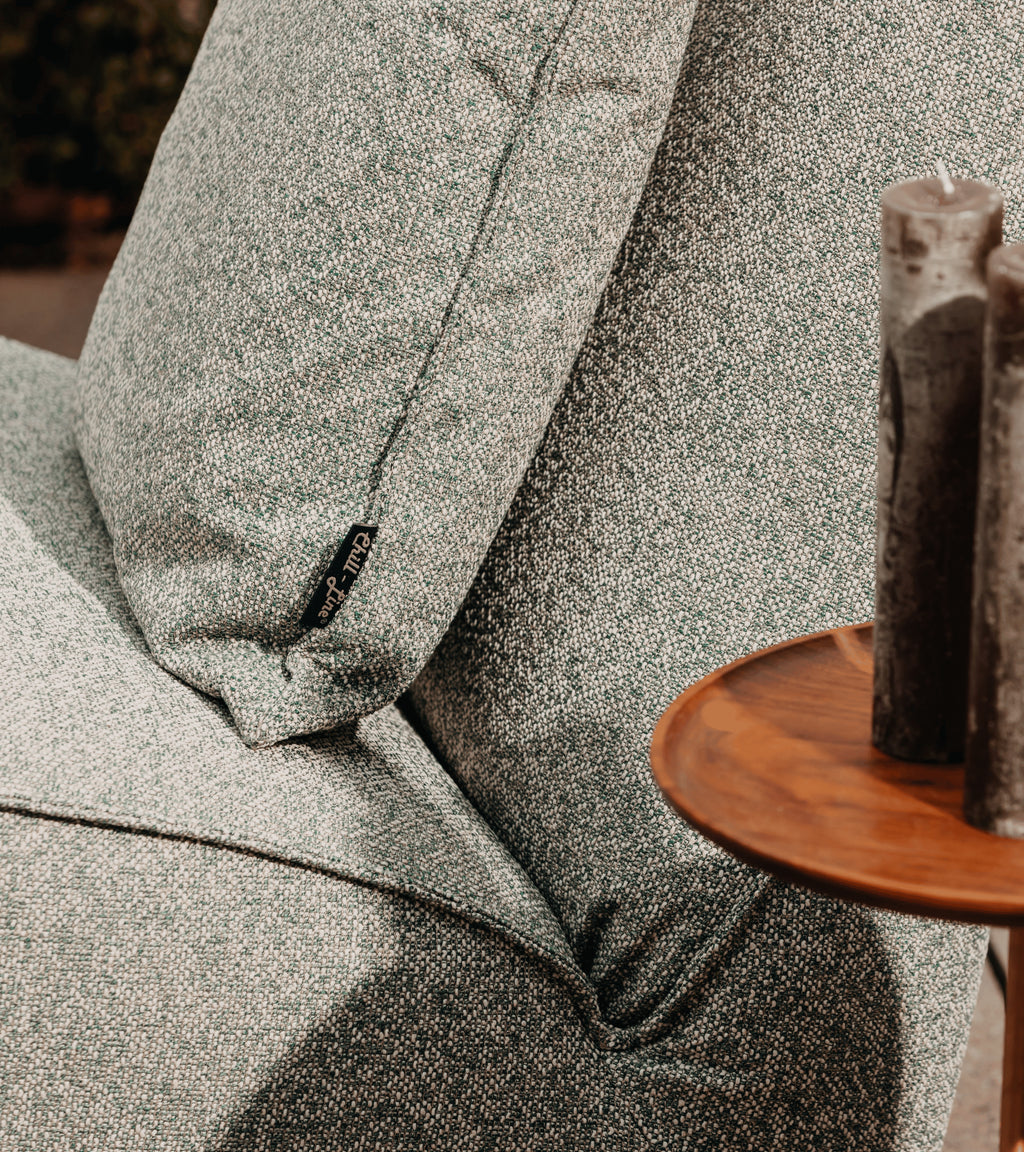 Groene lounge fauteuil van HoekbankXXL, met een geweven textuur en een klein merklabel op het kussen.
