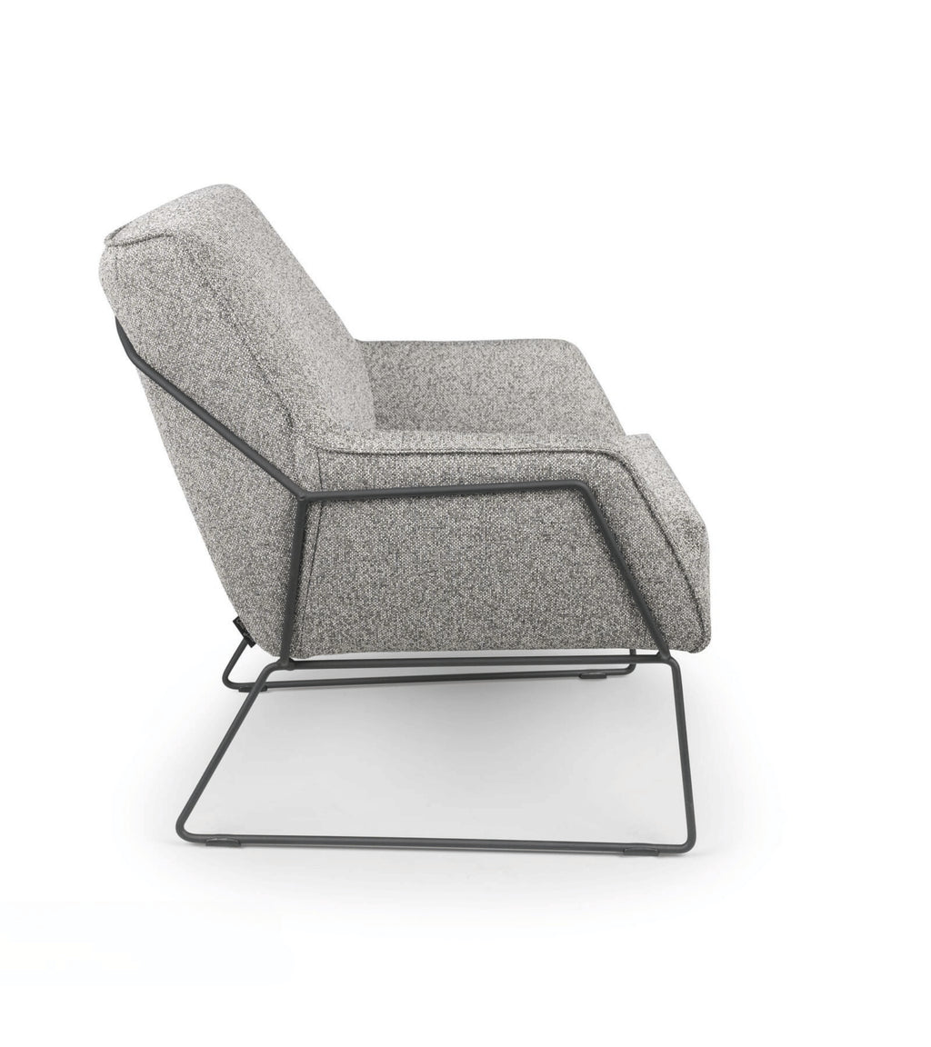 Grijze fauteuil, Rose van HoekbankXXL, met gestoffeerde bekleding en een metalen frame, in zijaanzicht.
