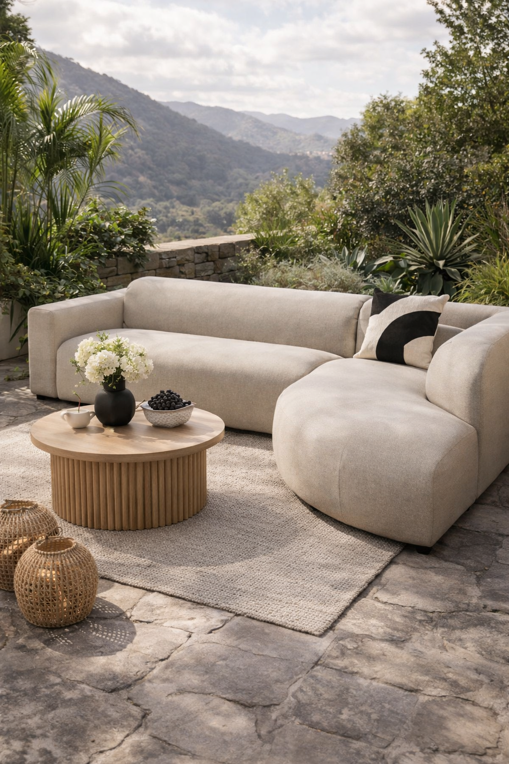 Beige loungebank tuin van HoekbankXXL met zwart-wit kussen op een terras met bergen op de achtergrond.
