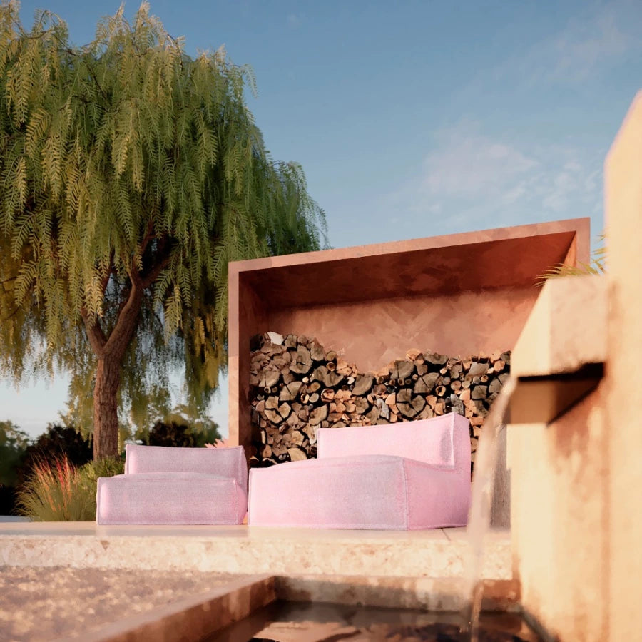 Roze silky 1-zits loungestoel buiten van HoekbankXXL, geplaatst bij een stapel houtblokken naast een waterval.
