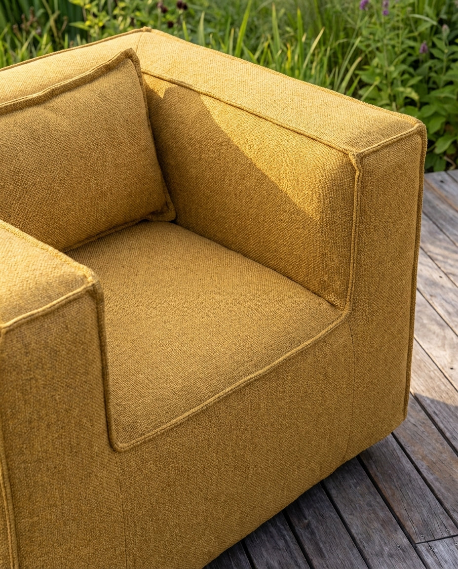 Gele clubfauteuil lounge stoel buiten van HoekbankXXL, met een grof geweven textuur, in een buitensetting.
