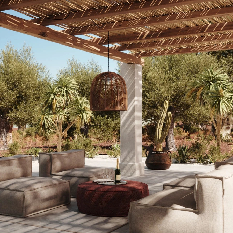 Zachte clubfauteuil loungestoel buiten van HoekbankXXL, in een lichte kleur, op een terras met buitenmeubilair en tropische beplanting.
