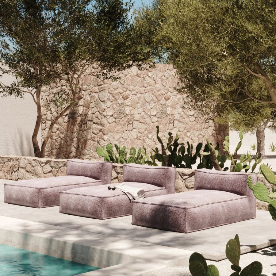 Roze silky longchair van HoekbankXXL, buiten geplaatst bij een zwembad met stenen muur en cactusplanten op de achtergrond.
